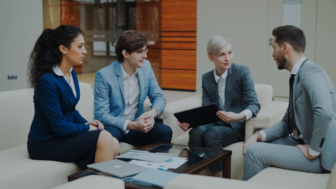 services-06 Businesswoman with digital tablet talking with male and female business colleagues sitting on couch in modern office indoors