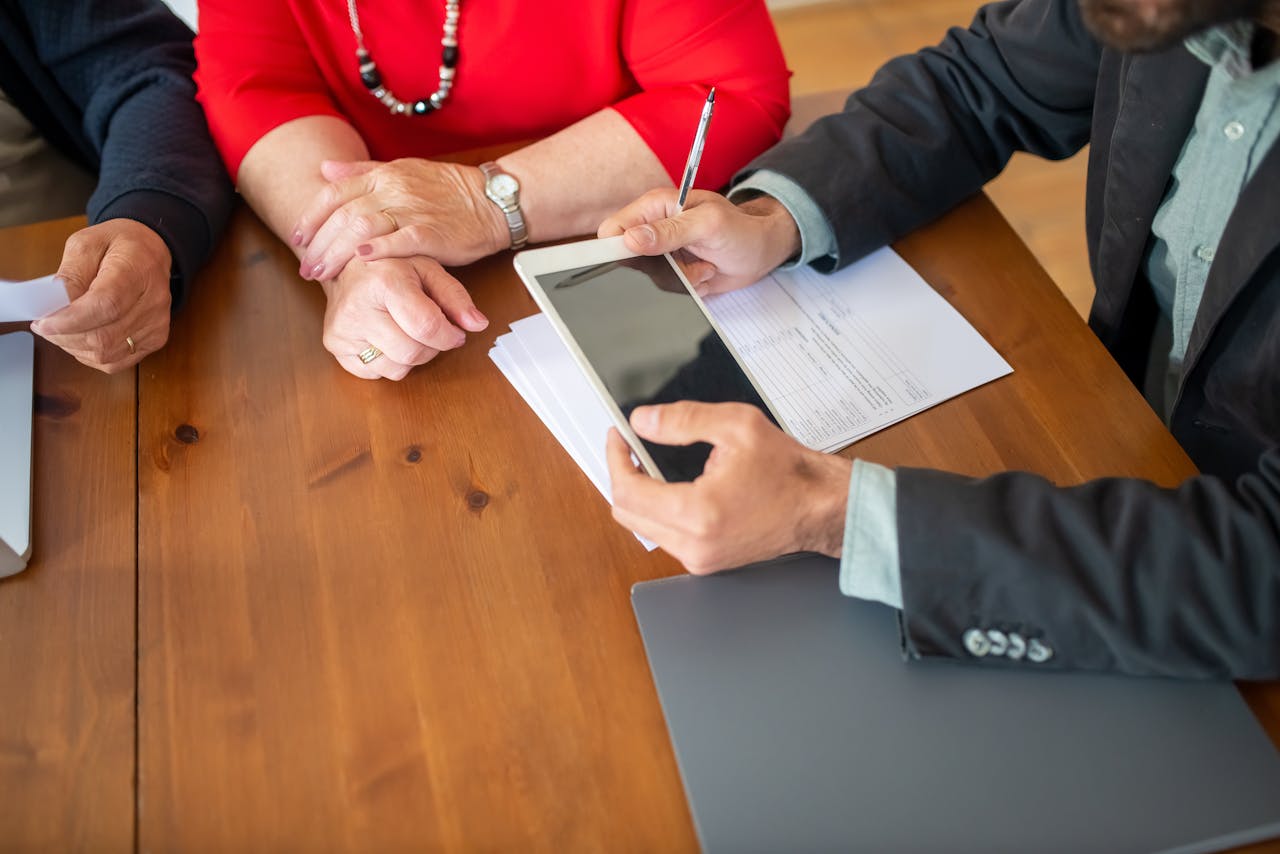 services-02 Business meeting at a wooden table with consultant reviewing documents and using a digital tablet.